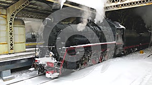 Vintage steam train starting from the station, winter time. Waiting for passengers to board at the platform