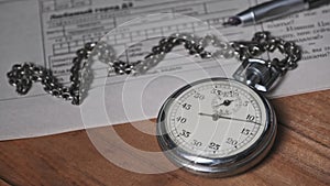 Vintage Stopwatch Lies on Wooden Desk with Old Documents and Counts Seconds