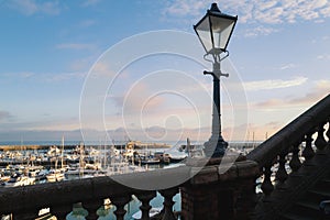 Vintage street lamp along a balustrade wall with a backdrop of Ramsgate Royal Harbour in late afternoon sunshine