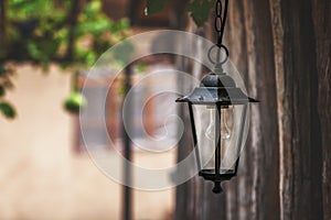 Vintage street lamp, black with glass accents, against a blurred nature background