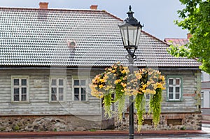 Vintage street lamp with hanging flower pots on rainy day