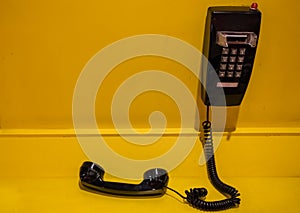 Vintage style black phone display on yellow wall