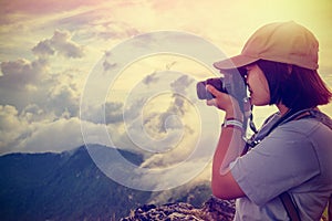 Vintage style hiker taking photo at sunset