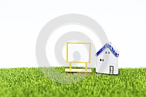 Vintage style house model with blank sign on green grass with space on white background