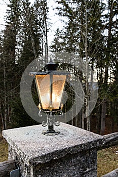 Vintage style lantern glowing on a stone column