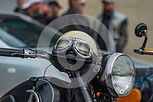 Vintage style motorbike helmet with goggles on the motorcycle handlebar