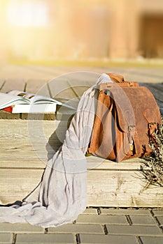 vintage natural leather backpack and books on gray rustic wooden stairs