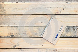 Vintage style of notebook and pen on the old wooden floor.