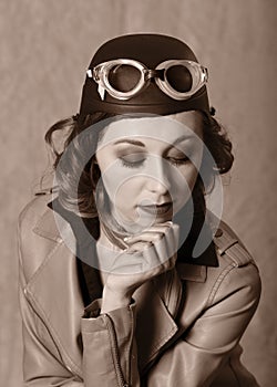 Vintage style portrait of aviator woman wearing goggles and leahter jacket