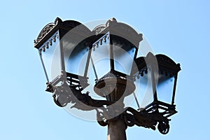 vintage style street light closeup. triple lantern. classic old cast iron metal body with frosted glass lens