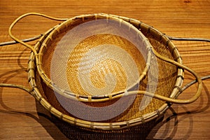 Vintage style woven bamboo colanders isolated on wooden table