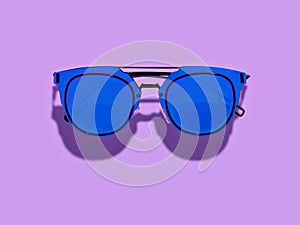 Vintage styled simple blue sunglasses on purple backgrpond.