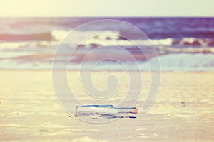 Vintage stylized message in a bottle on beach, shallow depth of