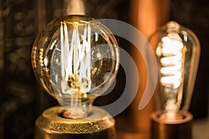 Vintage stylized round tungsten lamp glowing in dark, close-up photo with selective focus and shallow DOF