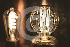 Vintage stylized round tungsten lamp glowing in dark, close-up photo with selective focus and shallow DOF