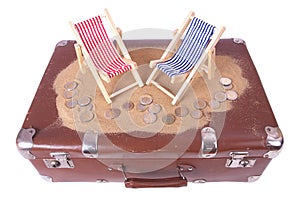 Vintage suitcase with euro coins lie in front of toy beach chair