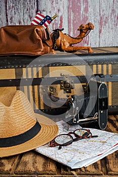 Vintage suitcase, map, glasses and an old camera on the table