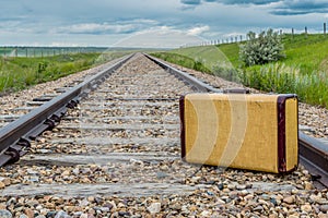 Vintage suitcase in middle of railroad tracks on the prairies
