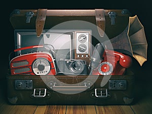 Vintage suitcase with old obsolete electronic equipment set. Retro technology concept background. Radio, tv set, telephone camera