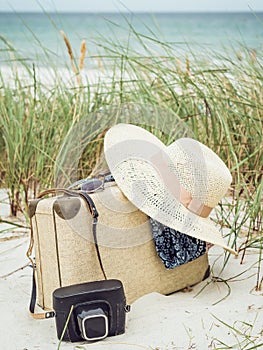 Vintage suitcase, summer hat, and a retro camera at sea