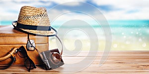 Vintage suitcase, sunglasses and hipster hat wooden deck and blur tropic sea background. Summer paradise cruise travel design