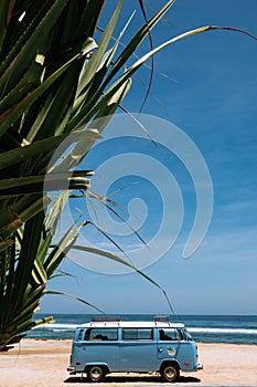 Vintage surf car parked on the tropical beach seaside. Leisure trip in the summer. Copy space