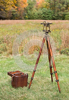 Vintage Surveyors Level (Transit, Theodolite) with wooden Tripod and Case in a field.