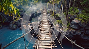 Vintage suspension wooden bridge in jungle, old dangerous footbridge across river. Landscape of tropical forest, rocks and blue