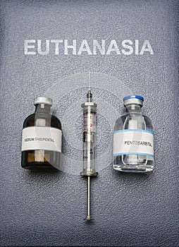 Vintage syringe and drugs used in lethal injection on a book of euthanasia, digital composition