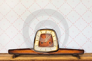 Vintage table clock in front of retro wallpaper