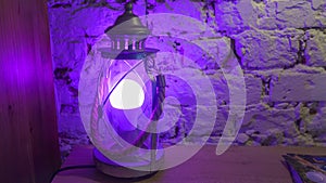 Vintage table lamp shines purple light on brick wall background