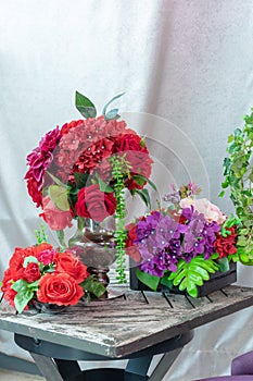 Vintage table with many plastic flowers and plants, fabric background