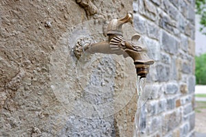 vintage tap with running water on outside wall. outdoor garden faucet on yard background