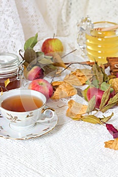 Vintage tea party - tea cups, apples and honey on white wooden table.