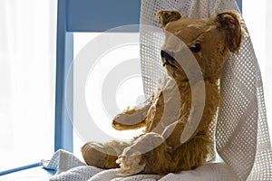 Vintage teddy bear sitting on blue nursery chair