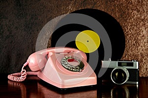 Vintage Telephone with Film Camera and Long Playing Record on a Polished Wooden Table Top