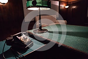 Vintage telephone and reading lamp on a table with green cloth