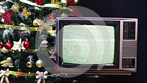 Vintage television turning on with Christmas tree and blinking lights behind