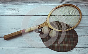 A vintage tennis racket with balls on wood background.