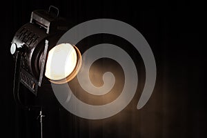 Vintage theater spot light on black curtain