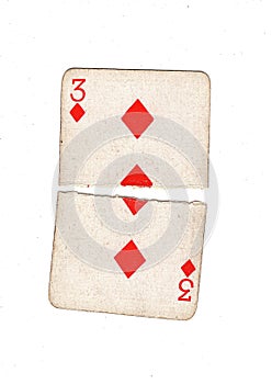 A vintage three of diamonds playing card torn in half.