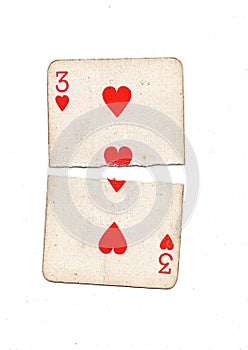 A vintage three of hearts playing card torn in half.