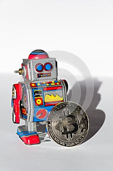 Vintage tin toy robot with bitcoin coin, cryptocurrency mining concept