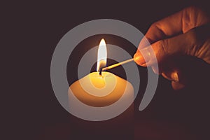 Vintage tone of hand with matchstick, lighting a candle photo