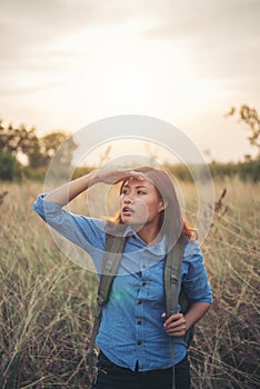 Vintage tone images of beautiful young hipster woman with backpack walking on meadow. Portrait of hiker girl outdoor.