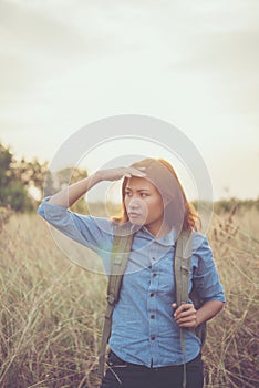 Vintage tone images of beautiful young hipster woman with backpack walking on meadow. Portrait of hiker girl outdoor.