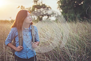 Vintage tone images of beautiful young hipster woman with backpack walking on meadow. Portrait of hiker girl outdoor.