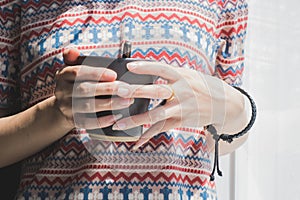 Vintage tone, soft focus, Asian girl's hand holding cup of coffee in the morning near the window