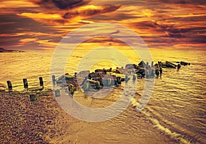 Vintage toned dramatic sunset over beach and rocky pier
