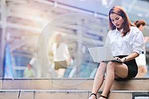 Vintage toned image of young business woman using laptop for job at outside office. Internet of things concept